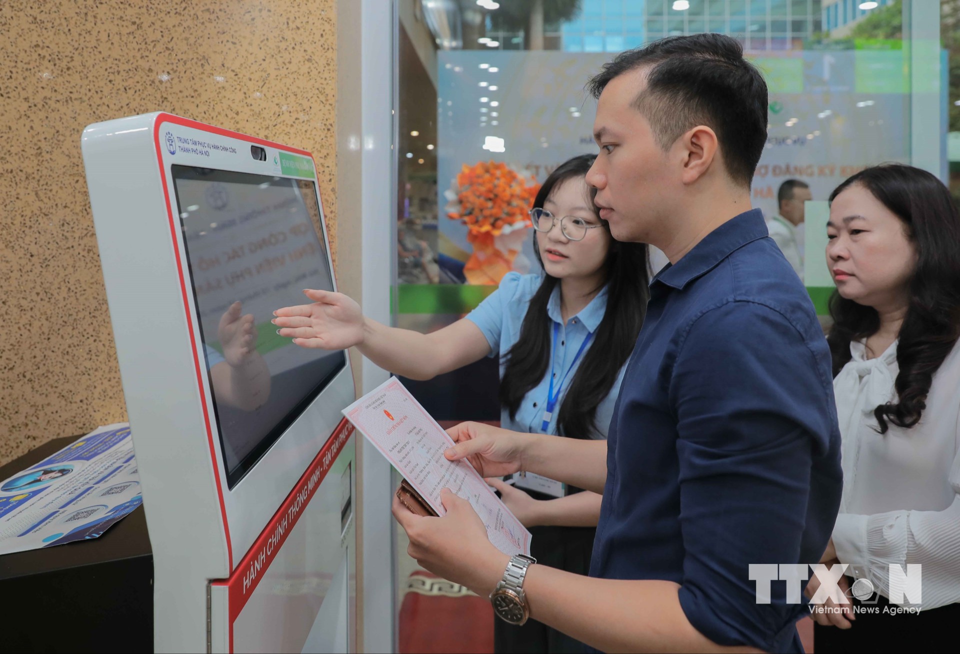 Anh Vũ Hải Hưng (phường Tây Mỗ, Hà Nội) rất hào hứng khi được nhân viên Trung tâm Phục vụ hành chính công thành phố Hà Nội tận tình hướng dẫn, giúp gia đình không mất thời gian tìm hiểu. (Ảnh: Phan Phương/TTXVN)